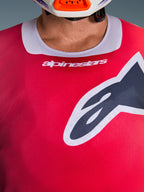 Alpinestars 2026 Racer Portl Jersey, nærbillede af bryst- og kraveområdet, rød med lysegrå halskant, hvid Alpinestars-tekst og stort Astars-logo, med en fugttransporterende teknisk tekstur