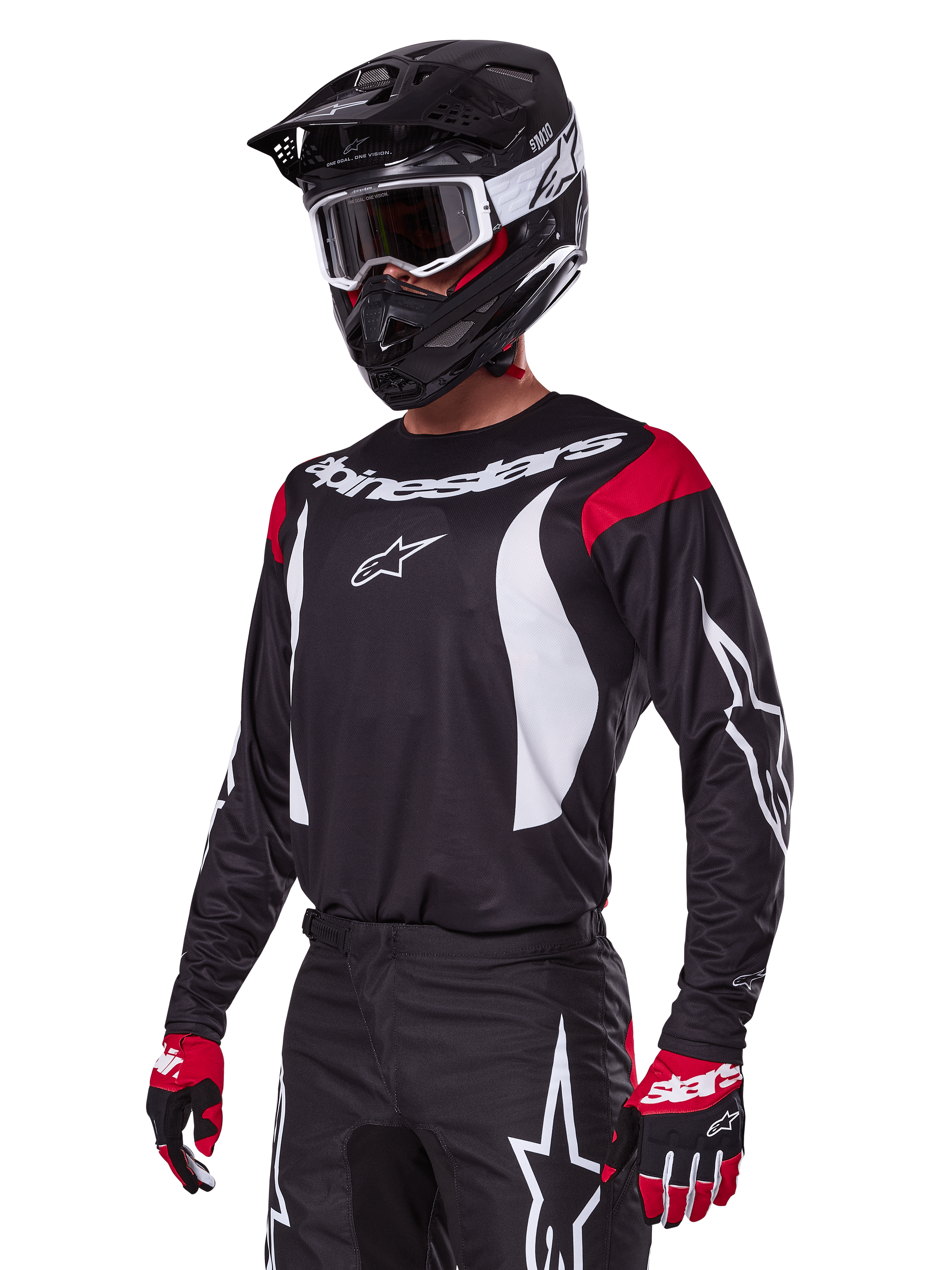 Motocross-kører iført Alpinestars 2025 Fluid Haul udstyrssæt, sort jersey med røde skulderpaneler og hvid grafik, matchende sorte bukser med hvide stjernelogoer, rød-sorte handsker, sort hjelm med hvide detaljer og goggles, koordineret motocross-beklædning.
