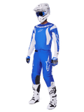 Motocross-rytter iført det komplette 2025 Fluid Haul Gear Set, blå og hvid trøje og bukser med Alpinestars-branding, hvid hjelm med blå goggles, hvide støvler og blå handsker, koordineret racersæt til off-road motocross.