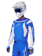 Alpinestars 2025 Fluid Haul-udstyrssæt, motocross-kører iført blåt og hvidt udstyr, blå jersey med hvide detaljer, blå bukser med stjernelogoer, hvid hjelm med blå goggles og blå og grå handsker, komplet outfit til terrænkørsel