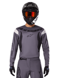 Motocross rider wearing the 2025 Fluid Haul Jersey and Gear Set, Gray with black and white accents, featuring long sleeves and bold branding, black helmet with orange goggles, and black gloves, coordinated outfit for off-road racing