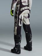 Alpinestars 2026 Racer Lahnd bukser, motocross-bukser, sand camo og grå, set bagfra med markant hvid branding på sædet og benene, kombineret med sorte motocross-støvler og gule handsker, professionelt off-road racingudstyr