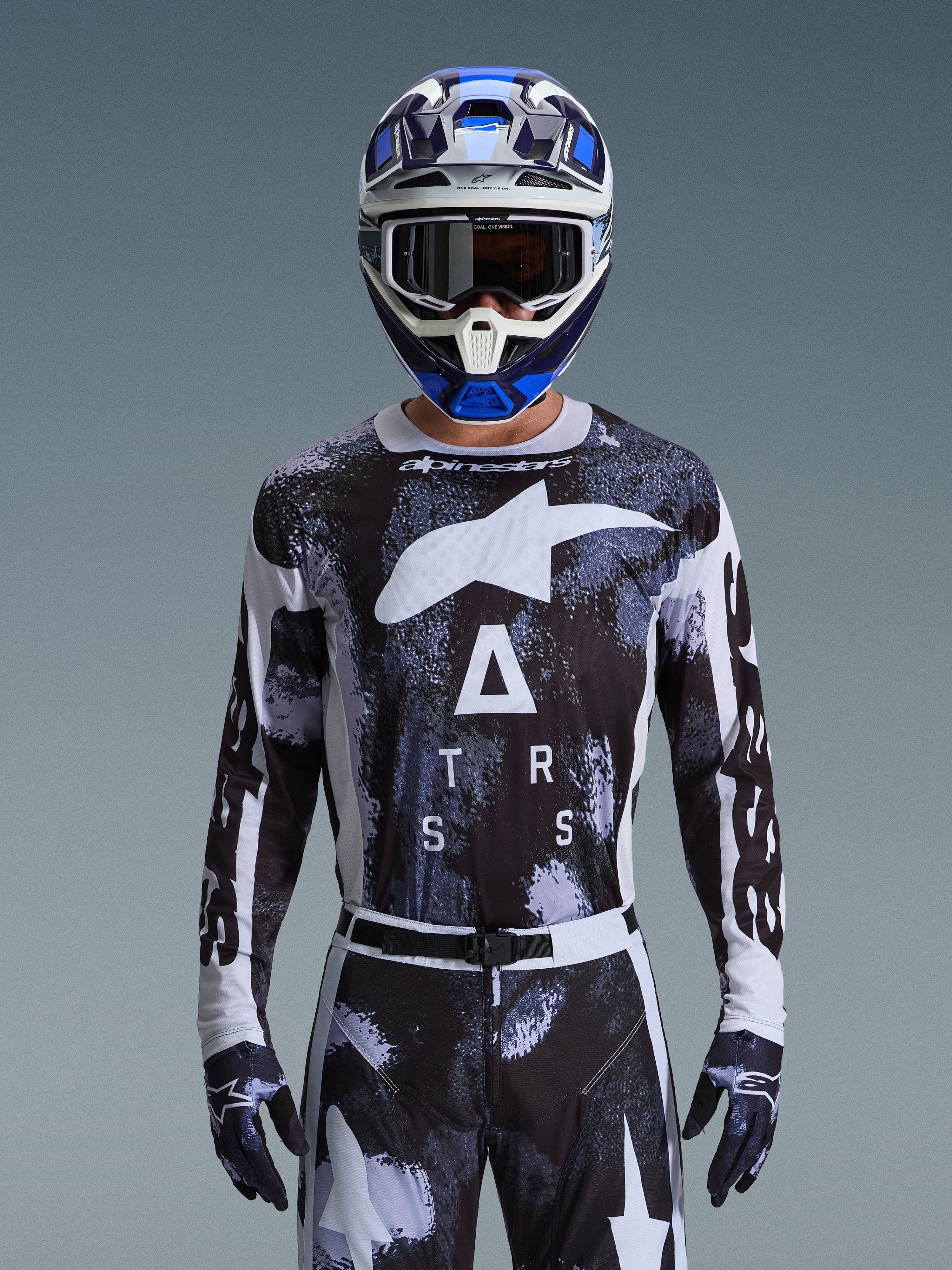 Alpinestars 2026 Racer Lahnd Jersey, motocross-udstyr, Iron Camo-mønster i sort og hvid, med et markant stjernelogo og ASTARS-skrift, vist med matchende bukser og en blå motocross-hjelm