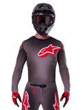 Alpinestars 2025 Supertech Lipan Jersey, motocross-trøje, Smoke og rød, med et stort rødt og hvidt logo på brystet, båret med en sort hjelm og røde og sorte handsker, atletisk race-pasform med laserskårne perforeringer