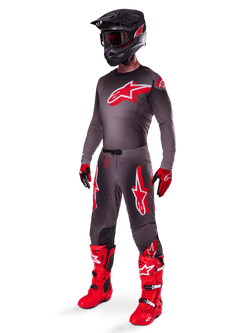 Alpinestars 2025 Supertech Lipan Gear Set, full motocross racing outfit, dark gray and red jersey with large star logo, matching pants with red accents and star graphics, red gloves, and bright red boots with white buckles, including a matte black helmet with red goggles.