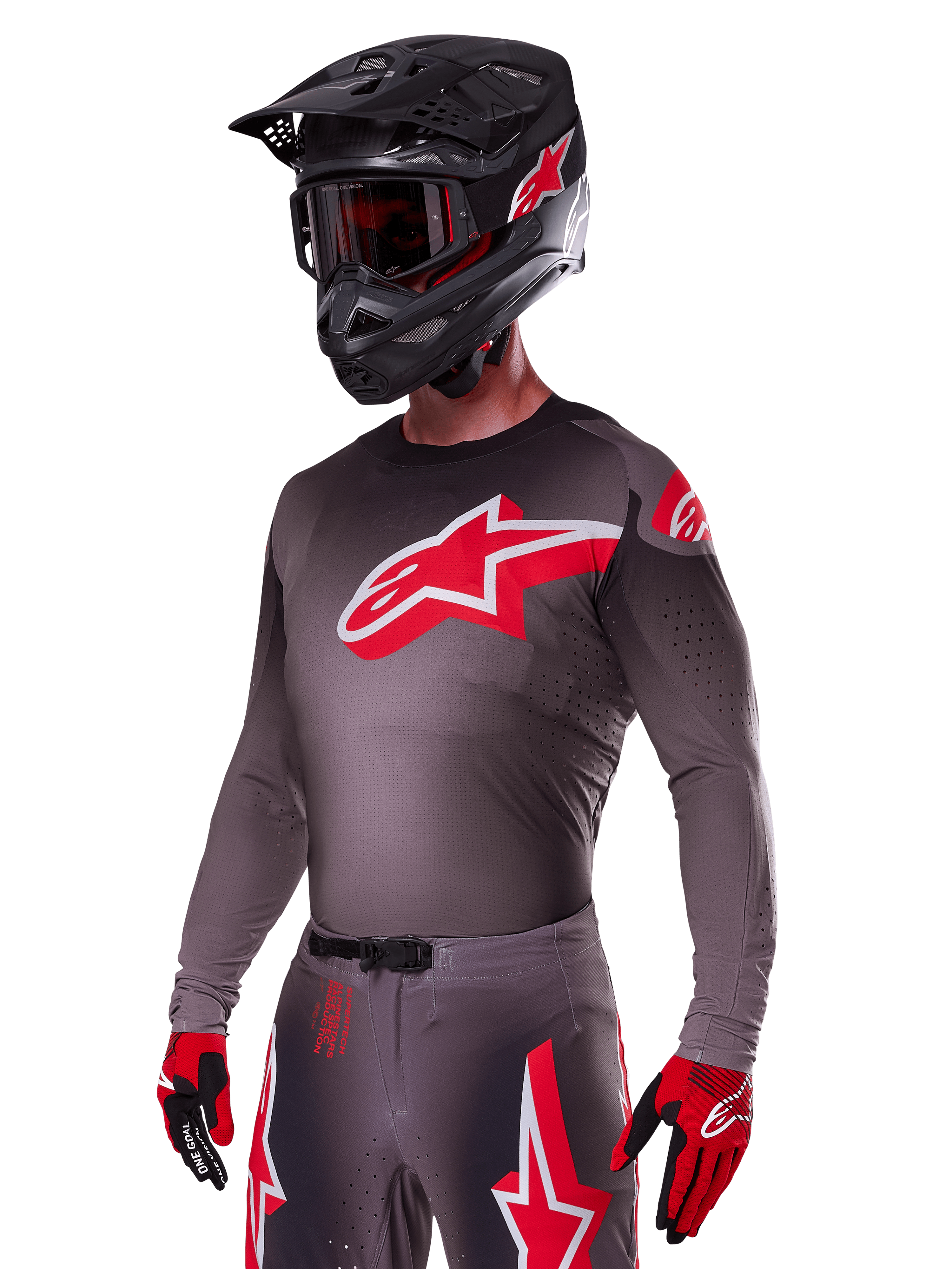 Alpinestars 2025 Supertech Lipan Gear Set, motocross-kører iført mørkegrå trøje og bukser med røde og hvide detaljer, stort rødt Alpinestars-logo på brystet, laserskårne perforeringer til ventilation, matchende sort hjelm, røde goggles og rød-sorte handsker.