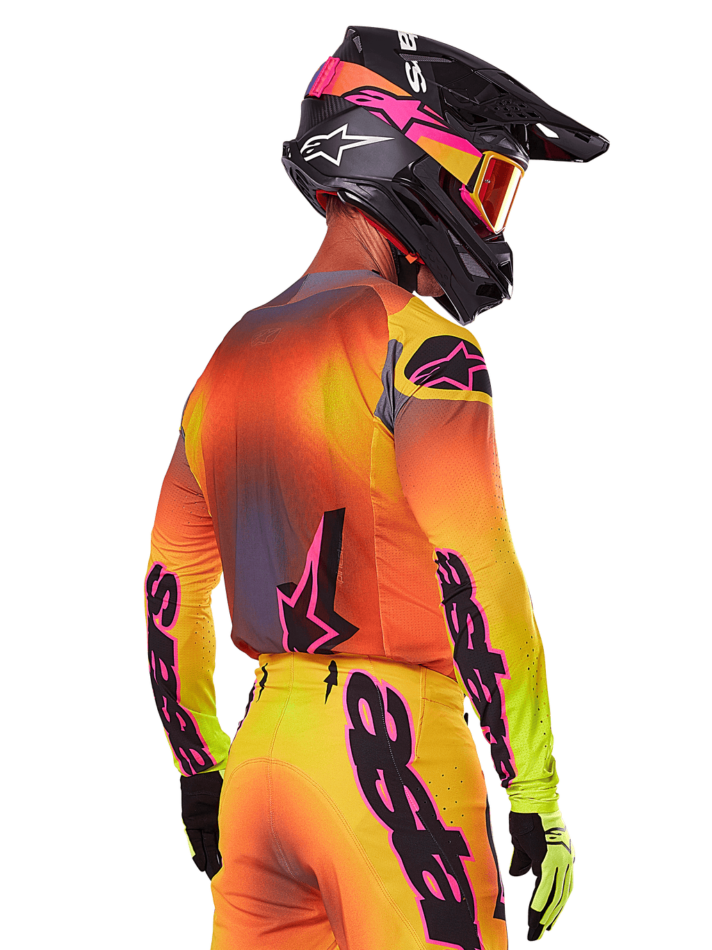 Motocross-kører set bagfra fra siden iført Alpinestars 2025 Supertech Lipan-udstyrssæt, med en gul, orange og rød gradient med sort og lyserød branding, sort hjelm med lyserøde detaljer og orange crossbriller, professionel beklædning til terrænkørsel.