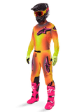 Motocross-kører iført Alpinestars 2025 Supertech Lipan Gear Set, gul og orange trøje og bukser med farveovergang og pink detaljer, sort hjelm med røde og gule goggles, stærke gule handsker og klare pink støvler, koordineret outfit til terrænkørsel