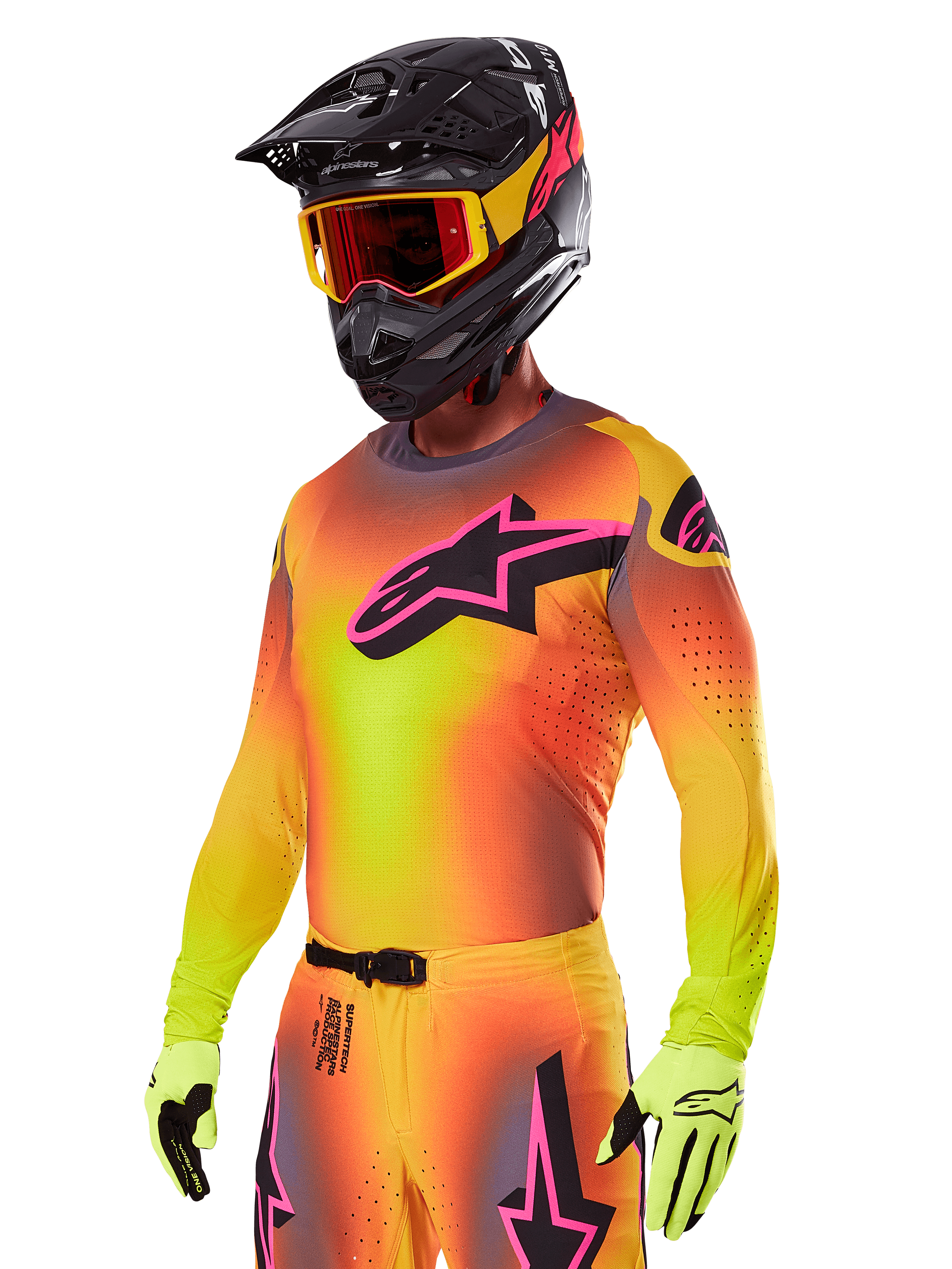 Motocrosskører iført Alpinestars 2025 Supertech Lipan-udstyrssæt, med en jersey med gul og orange farveovergang og et lyserødt og sort Astars-logo, neongule handsker og en sort hjelm med røde briller, professionelt terrænkørselsudstyr.