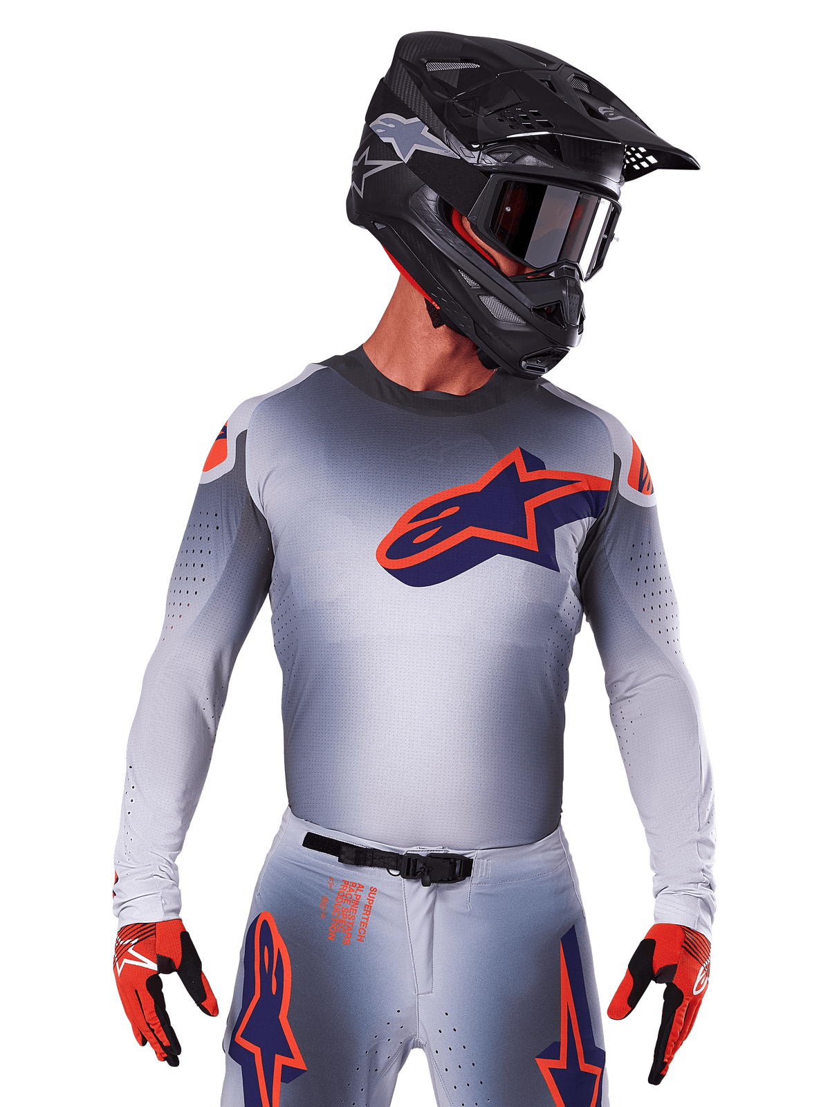 Alpinestars 2025 Supertech Lipan Jersey, motocross racertrøje, grå med orange og mørkeblå detaljer, langærmet performance-top med perforerede ventilationsdetaljer, vist med sort hjelm og røde handsker, strømlinet racerdesign