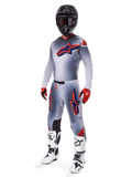 Alpinestars 2025 Supertech Lipan Gear Set, motocross-racerudstyr, grå med fluoriserende orange og mørkeblå stjernegrafik, båret med sort hjelm, røde og sorte handsker og hvid-sorte støvler, komplet professionelt off-road outfit med ventileret design