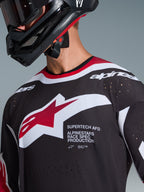Alpinestars 2026 Supertech AFD Vista trøje, sort, rød og hvid, nærbillede af brystet, der viser Alpinestars stjerne-logo og 'Supertech AFD'-tekst, med laserskårne ventilationshuller og mesh-konstruktion, båret med sort motocrosshjelm.