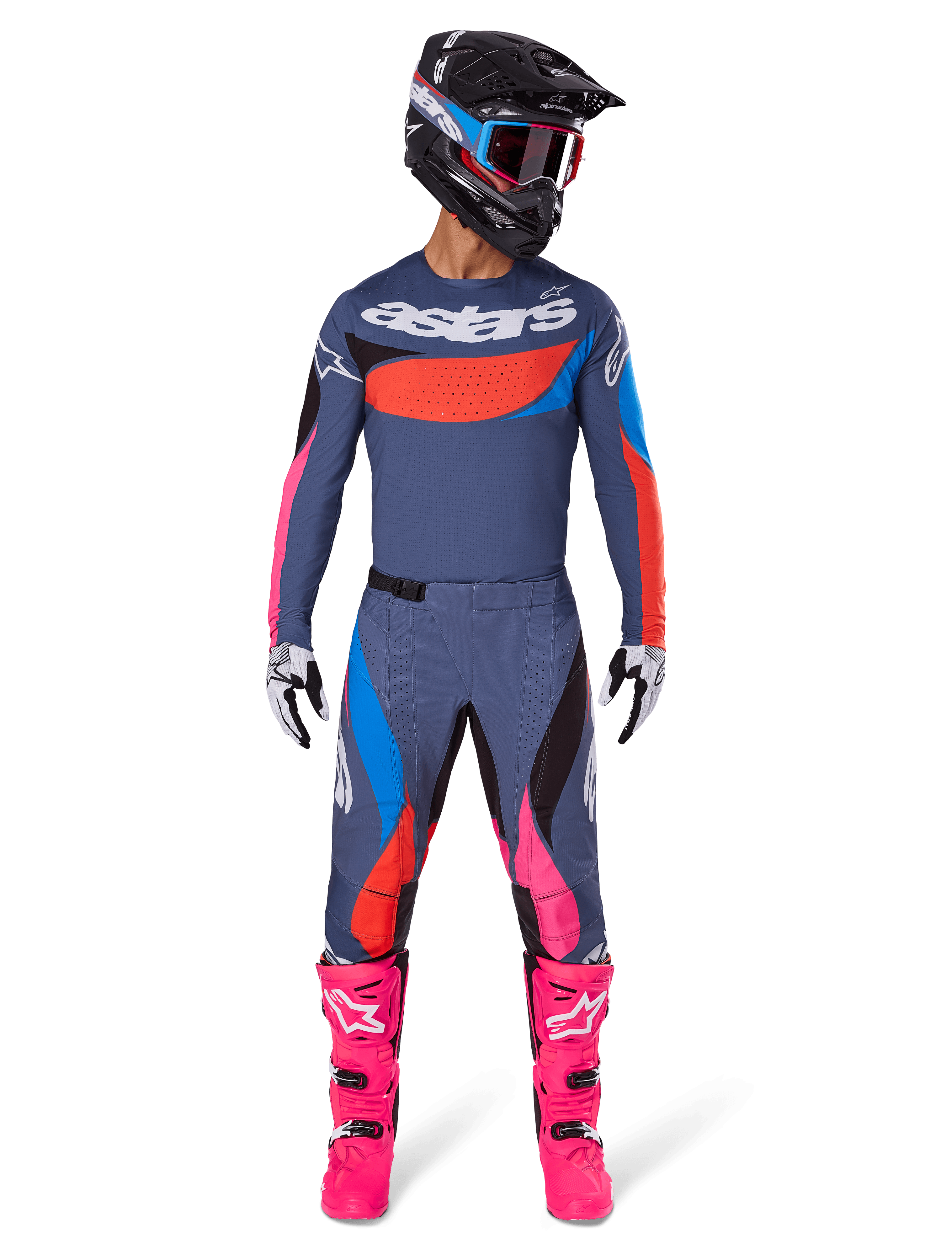 Alpinestars 2025 Techstar Dreem Gear Set, motocrosskører i fuldt racerudstyr, gråblå trøje og bukser med livlige lyserøde, orange og cyanblå detaljer, stort 'astars'-logo på brystet, skrigende lyserøde støvler, sort hjelm med goggles, koordineret sæt til professionel motocross