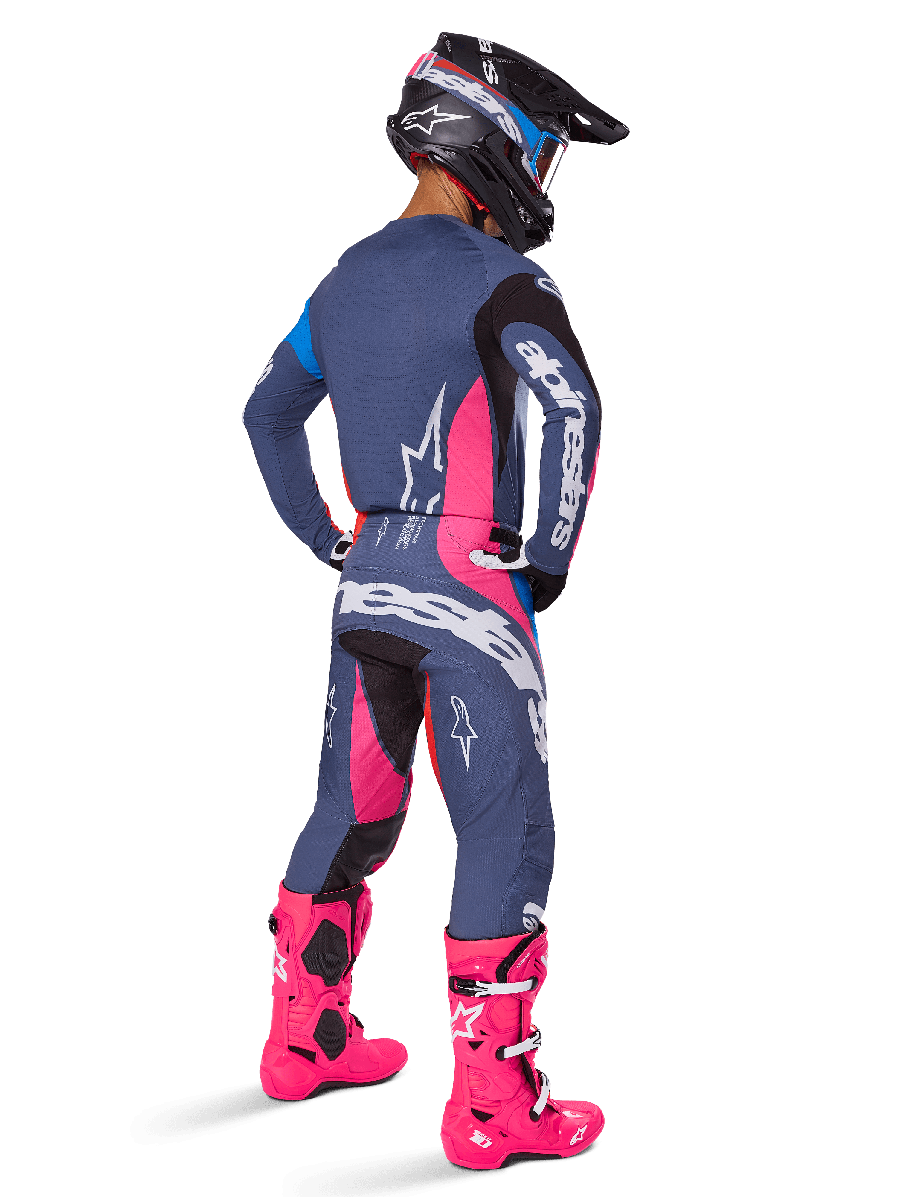 Motocrosskører set bagfra, iført Alpinestars 2025 Techstar Dreem-udstyrssæt, grå med markante lyserøde og hvide detaljer, sort og hvid hjelm og stærkt lyserøde støvler, komplet raceroutfit til motocross-performance.