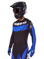 Motocross rider wearing the Alpinestars 2025 Techstar Dreem Gear Set, Black jersey with blue perforated-style panels and white branding, matching black and blue pants, black racing helmet, and blue gloves, coordinated performance outfit for off-road motocross.