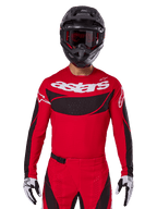 Alpinestars 2025 Techstar Dreem trøje, motocross-udstyr, klar rød og sort, med hvidt 'astars'-logo og sort ventileret brystpanel, bæres med matchende bukser, sort hjelm og hvide og sorte handsker, designet til professionel off-road racing