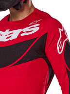 Alpinestars 2025 Techstar Dreem jersey, motocross-jersey, klar rød og sort, nærbillede af bryst og skulder med hvid branding, sorte diagonale paneler med laserskårne perforeringer til ventilation, atletisk racerpasform til off-road performance