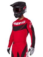 Alpinestars 2025 Techstar Dreem-udstyrssæt, rød motocross-jersey og bukser med sorte og hvide detaljer, her vist med sort hjelm og goggles, hvide og sorte handsker, med markant 'astars'-branding, designet til højtydende off-road-kørsel