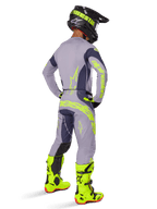 Motocross rider from a rear view wearing the Alpinestars 2025 Techstar Dreem Gear Set, Gray and Dark Gray with fluorescent yellow branding, matching jersey and pants, black helmet with yellow accents, and bright fluorescent yellow boots, coordinated professional motocross racing outfit.