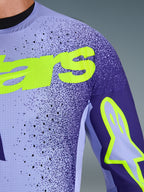 Alpinestars 2026 Supertech Scenz Jersey, motocross-trøje, lilla og gul fluo, nærbillede af det perforerede strækmesh-materiale og den lysende gule Alpinestars-branding på brystet og ærmet