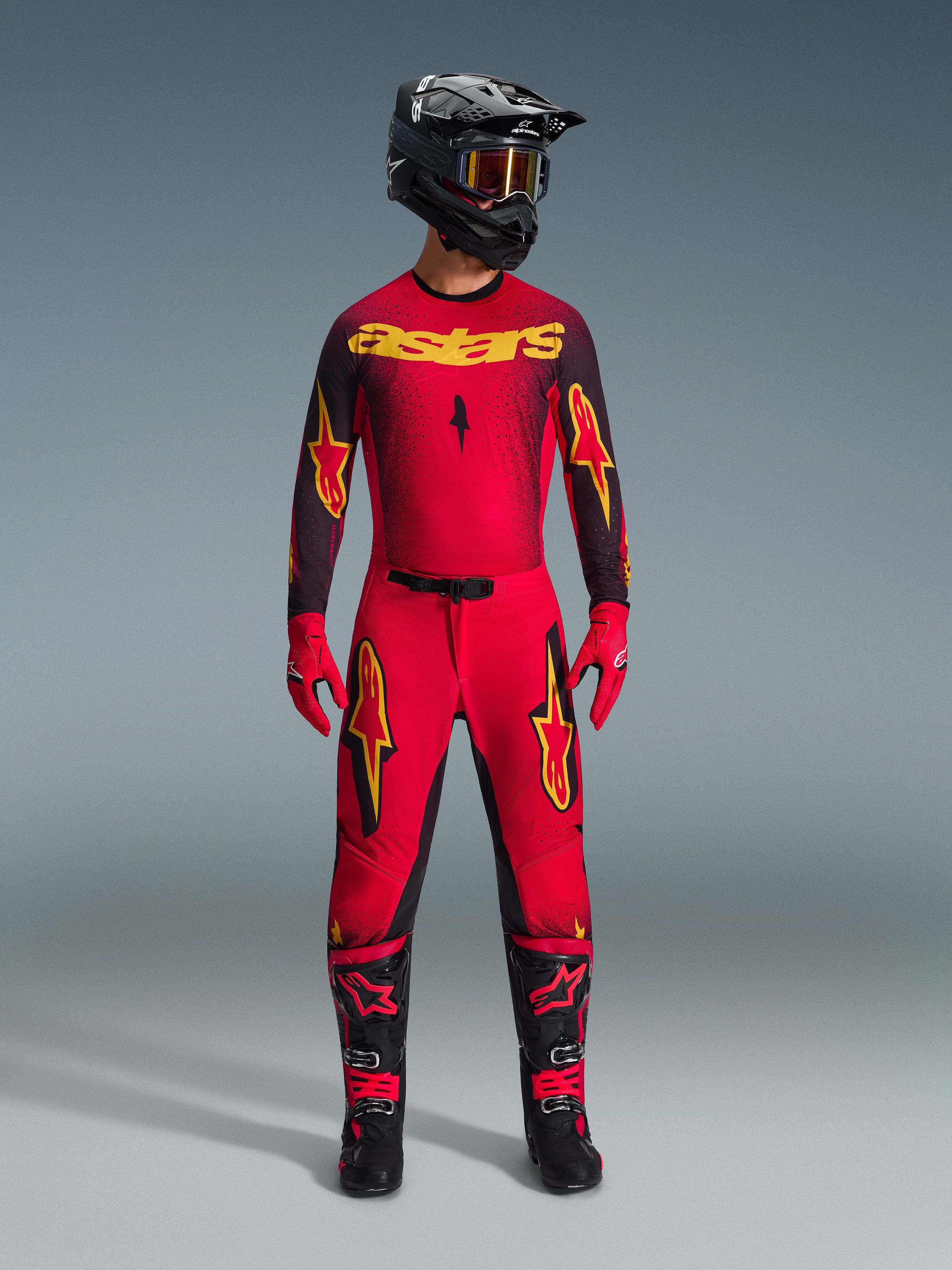 Alpinestars 2026 Supertech Scenz udstyrssæt, komplet motocross-raceroutfit i rød og sort med gul grafik, bestående af en professionel jersey og matchende bukser, båret med sort hjelm, røde handsker og sorte racingstøvler, premium udstyr til off-road konkurrence