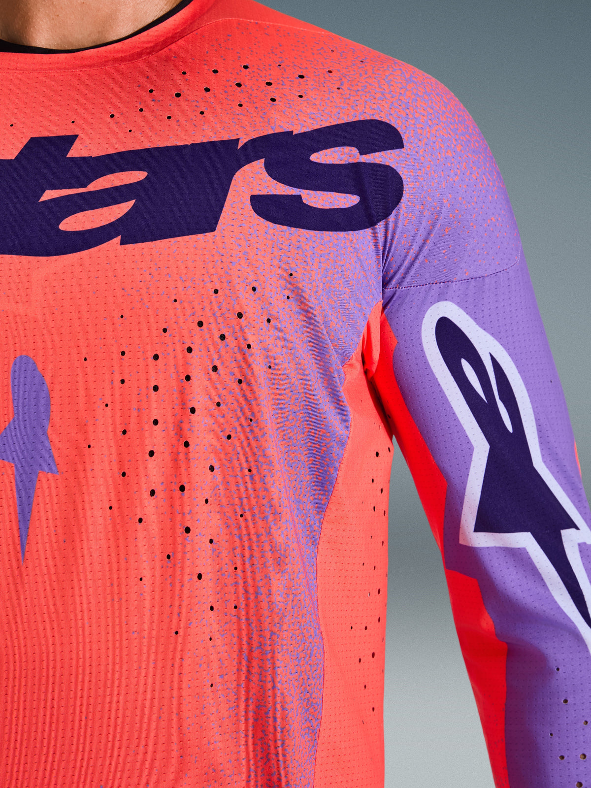 Alpinestars 2026 Supertech Scenz Jersey, motocross-trøje, Hot Coral og lilla, nærbillede der viser åndbar mesh-tekstur og laser-skårne perforeringer, med stort lilla brystlogo og grafik på ærmerne til professionel terrænkørsel.