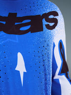 Alpinestars 2026 Supertech Scenz Jersey, nærbillede af Ucla Blue og hvidt design, laserskårne perforeringer til ventilation, sort 'stars' branding, åndbart mesh-stof til professionel motocross-racing