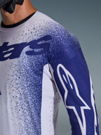 Alpinestars 2026 Supertech Scenz-trøje, lysegrå og mørkeblå, nærbillede af skulder og bryst med laserskårne perforeringer, hvidt Astars-logo på blåt ærme, nistret grafisk design, professionelt motocross-racerudstyr