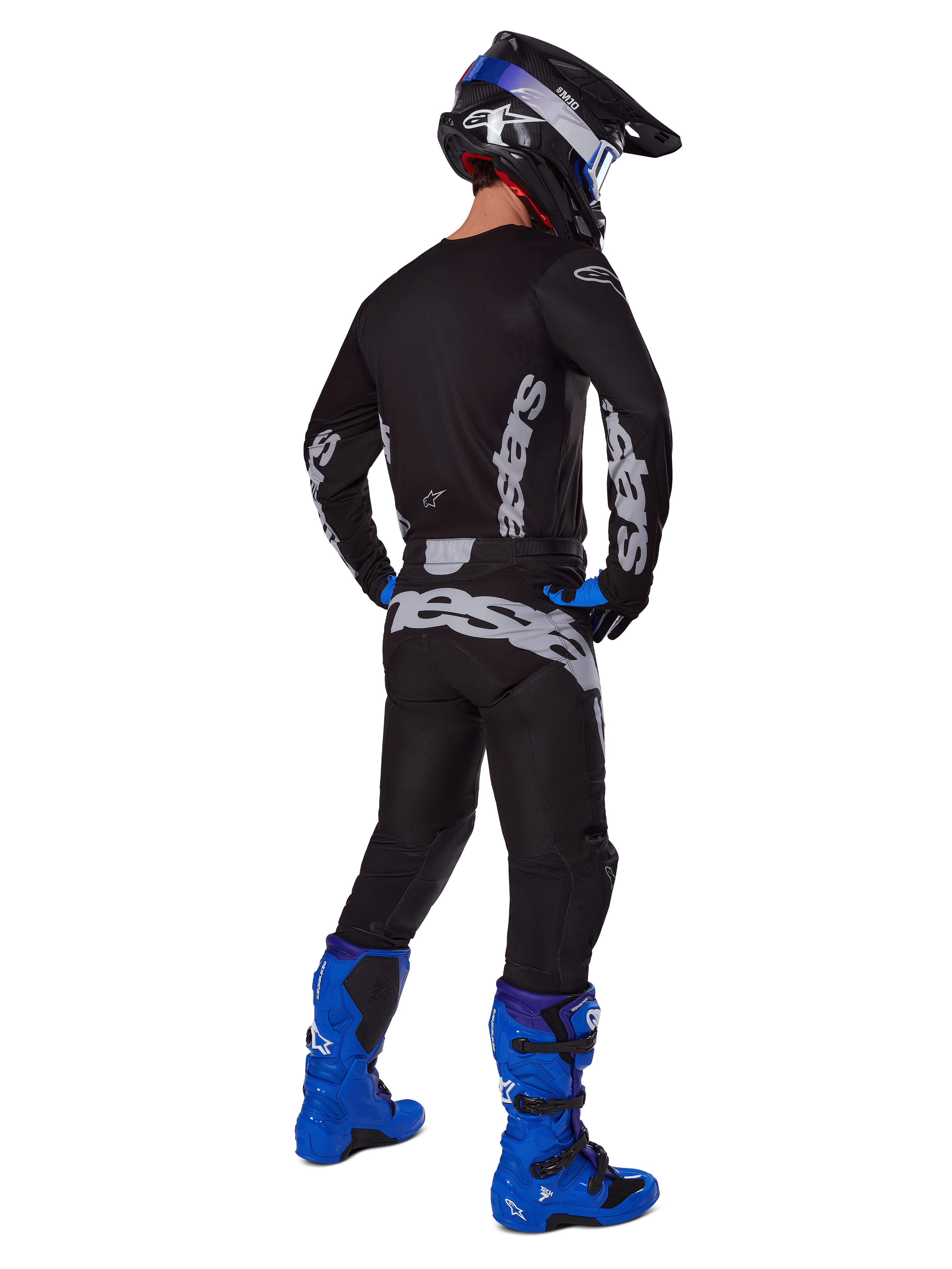 Alpinestars 2025 Racer Graphite Gear Set, motocrosskører set bagfra, sort og grå trøje og bukser med grå branding, kombineret med klare blå motocrossstøvler, en sort og blå hjelm og blå handsker, komplet præstationsorienteret off-road outfit.