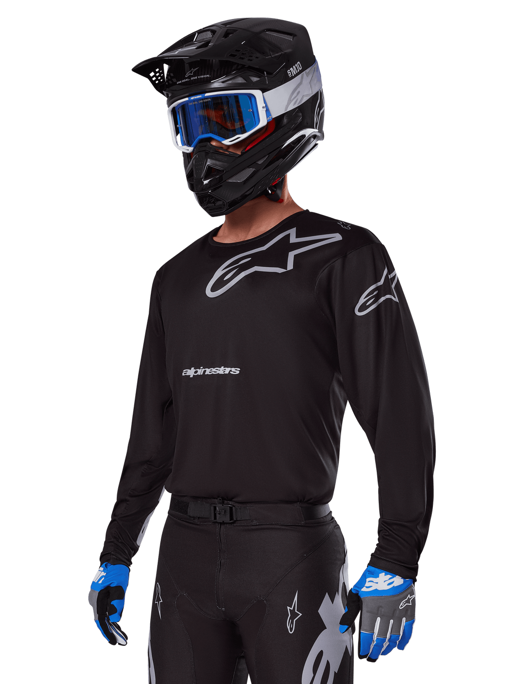 Motocross-kører iført Alpinestars 2025 Racer Graphite-udstyrssæt, sort jersey med grå Alpinestars-logoer, matchende sorte bukser med grå detaljer, sort hjelm med blå og hvide goggles, blå og grå handsker, strømlinet teknisk outfit til terrænkørsel