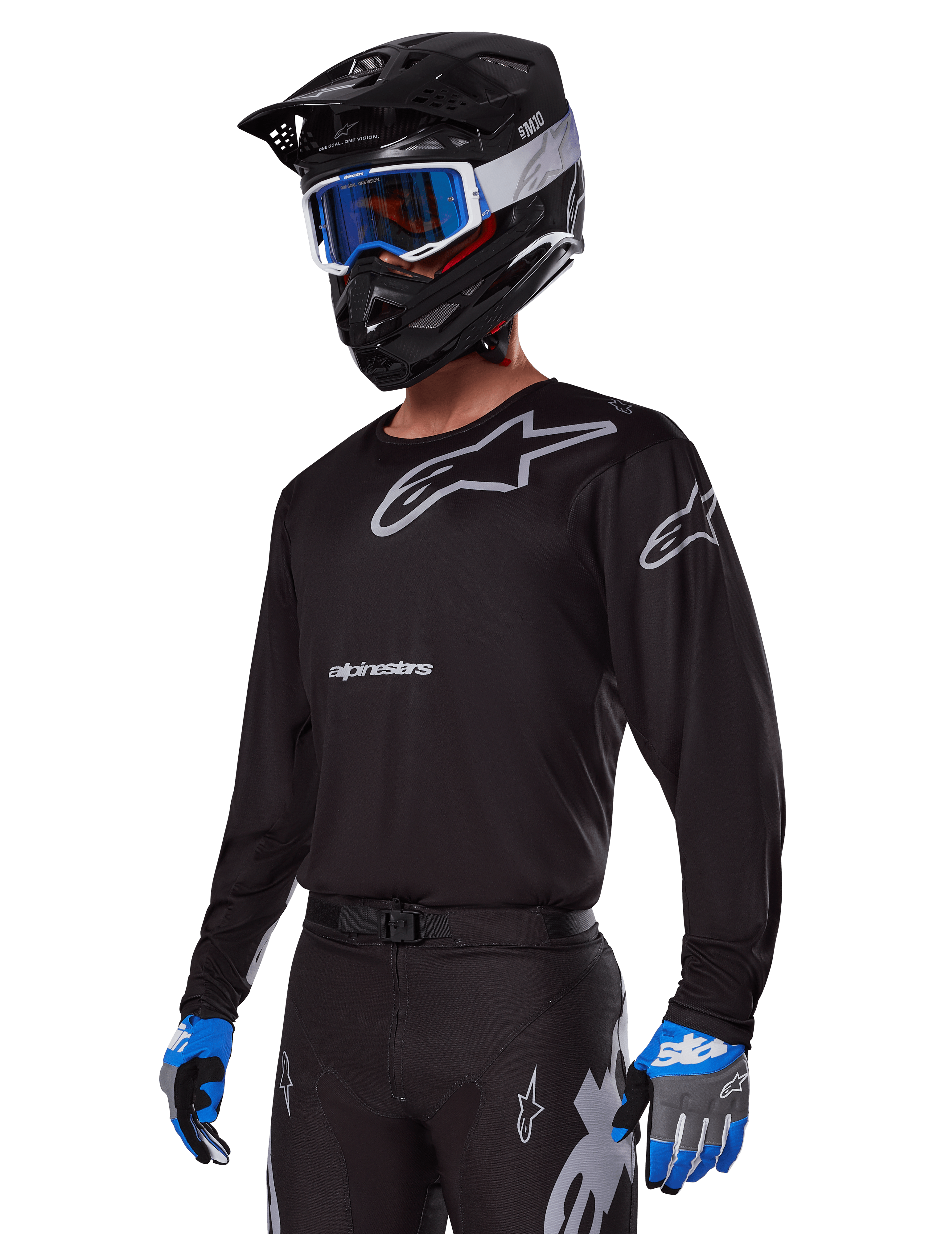 Motocross-kører iført Alpinestars 2025 Racer Graphite-udstyrssæt, sort jersey med grå Alpinestars-logoer, matchende sorte bukser med grå detaljer, sort hjelm med blå og hvide goggles, blå og grå handsker, strømlinet teknisk outfit til terrænkørsel