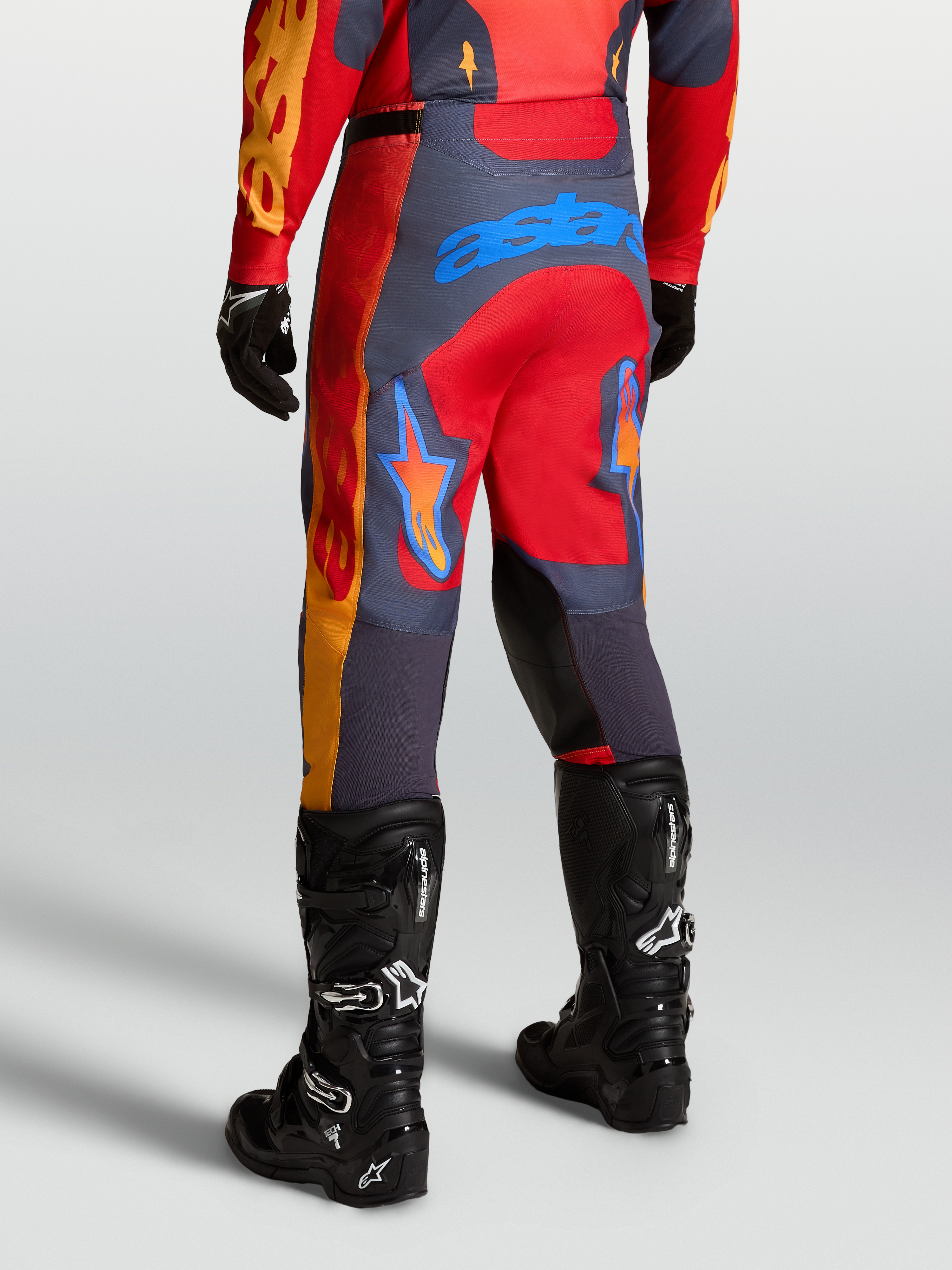 Alpinestars Racer Hunt bukser, rød og grå motocrossbukser til mænd, set bagfra i kørestilling med forstærkede paneler og logo