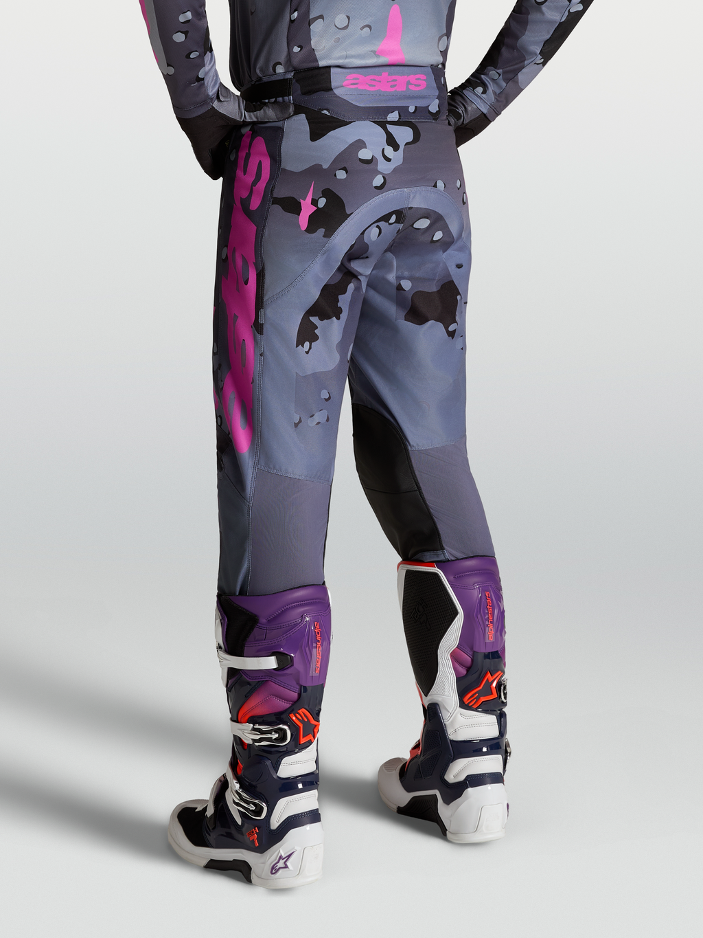 Alpinestars Racer Lone Bukser, motocrossbukser i grå camouflage og lilla, set bagfra på model med Tech 7 støvler, slidstærkt materiale til terrænkørsel.