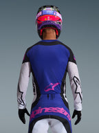 Bagfra-visning af en motocross-kører iført 2026 Techstar Knif Jersey i Black Light Gray Purple, med et lilla rygpanel med et lyserødt Alpinestars-logo, lysegrå ærmer med sorte detaljer og laserudskårne perforeringer, koordineret med en matchende lyserød og lilla hjelm og sorte handsker.