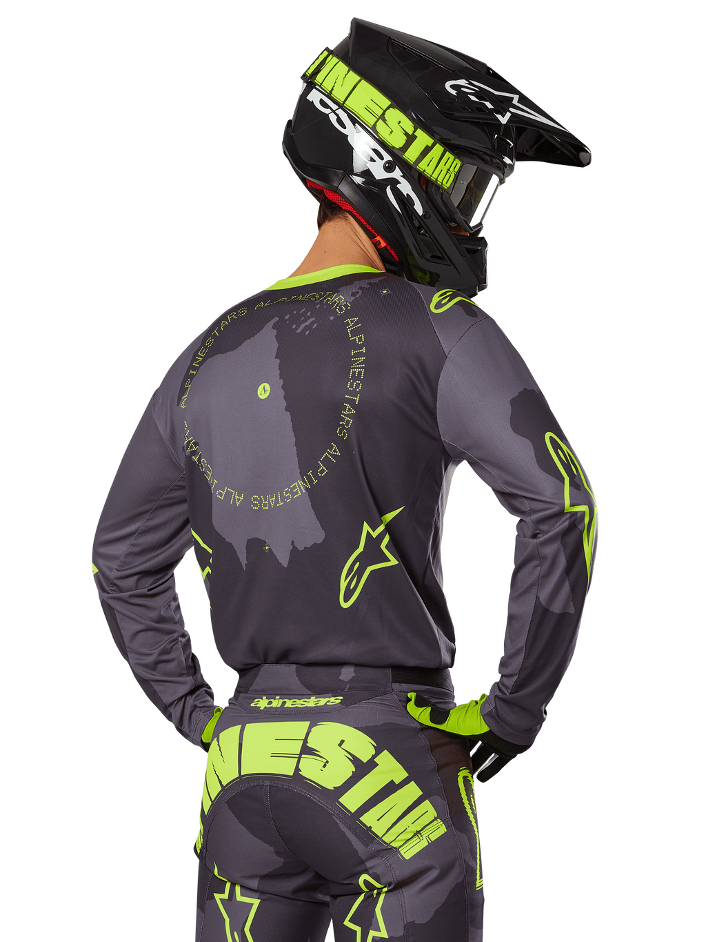 Alpinestars 2025 Racer Hollow Gear Set, motocross-kører set bagfra, grå trøje med fluorescerende gul cirkulær tekst og stjernelogoer, matchende grå og gule bukser med iøjnefaldende branding over sædet, sort og limegrøn hjelm, koordineret outfit til off-road racing