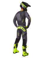 Alpinestars 2025 Racer Hollow Gear Set, motocross-udstyr set bagfra, Dark Camo Yellow Fluo, grå camo-trøje med neongule detaljer, matchende motocrossbukser med markant logo på sædet, neongule støvler og sort hjelm med gule briller.