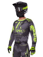 Alpinestars 2025 Racer Hollow udstyrssæt, motocross jersey og bukser i grå og neongul, båret med matchende sort hjelm, crossbriller og handsker, med markant fluorescerende gul Alpinestars-branding og stjernegrafik på en mønstret grå base, koordineret professionelt off-road racerlook