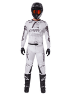 Alpinestars 2025 Racer Hollow Gear Set, hvidt med sort og grå grafik, komplet motocross-raceroutfit inklusiv trøje og bukser, bæres med sort hjelm, orange briller, sorte handsker og sorte støvler, højtydende off-road beklædning