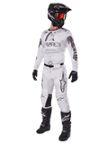 Alpinestars 2025 Racer Hollow-udstyrssæt, motocross-outfit, hvid og grå, trøje og bukser med markant 'STARS'-branding, sort hjelm med rød-orange tonede goggles, sorte handsker og sorte støvler, komplet professionelt udstyr til terrænkørsel