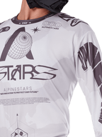 Nærbillede af Alpinestars 2025 Racer Hollow Jersey, hvid og grå, med sorte grafiske print, globus-logo og binær kode, teknisk motocross-beklædning til off-road kørsel