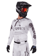 Alpinestars 2025 Racer Hollow-udstyrssæt, motocross-jersey og -bukser, hvid med sort og grå grafik, med 'ASTARS'-branding og hule globus-designs, båret med sort hjelm, røde goggles med spejleffekt og sorte handsker, designet til off-road-performance