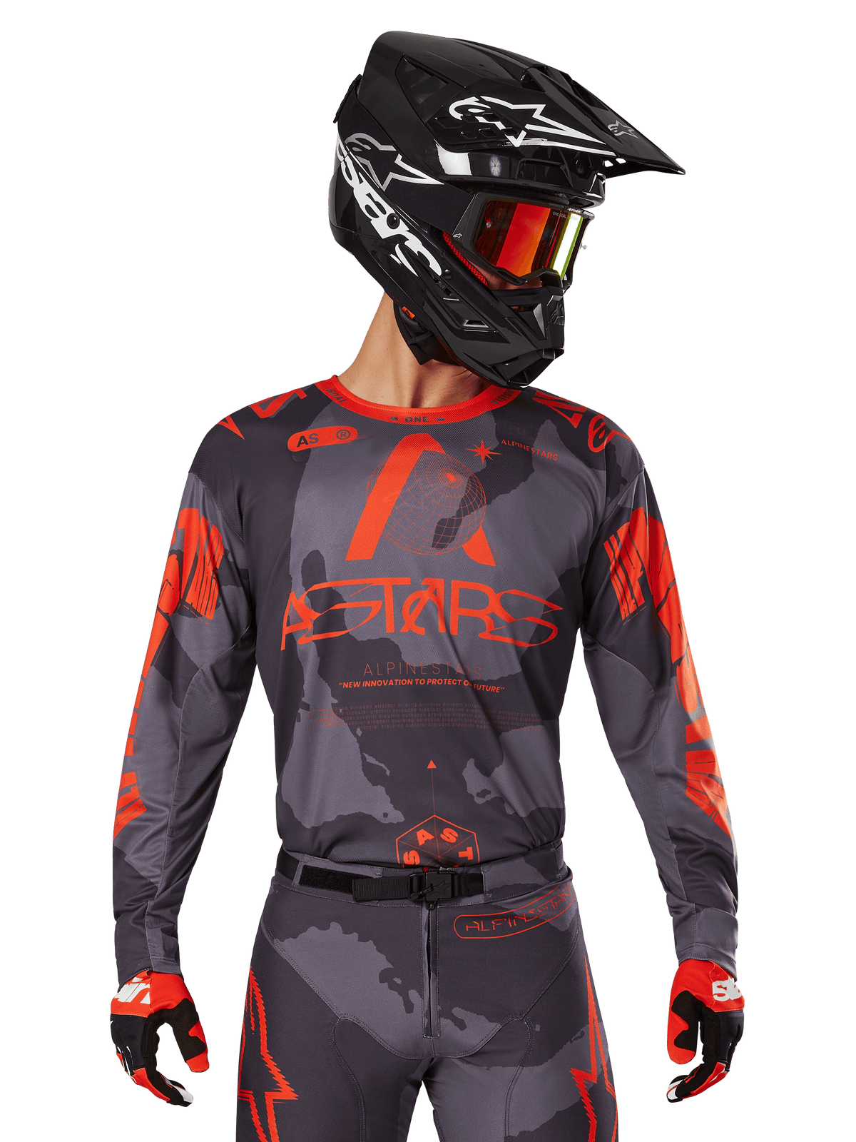 Alpinestars 2025 Racer Hollow Jersey, motocross trøje, grå camouflage og neon orange, person iført matchende udstyrssæt med bukser og handsker, sort hjelm med hvide designs og spejlede goggles, markant ASTARS-branding, beskyttende off-road racing sportstøj