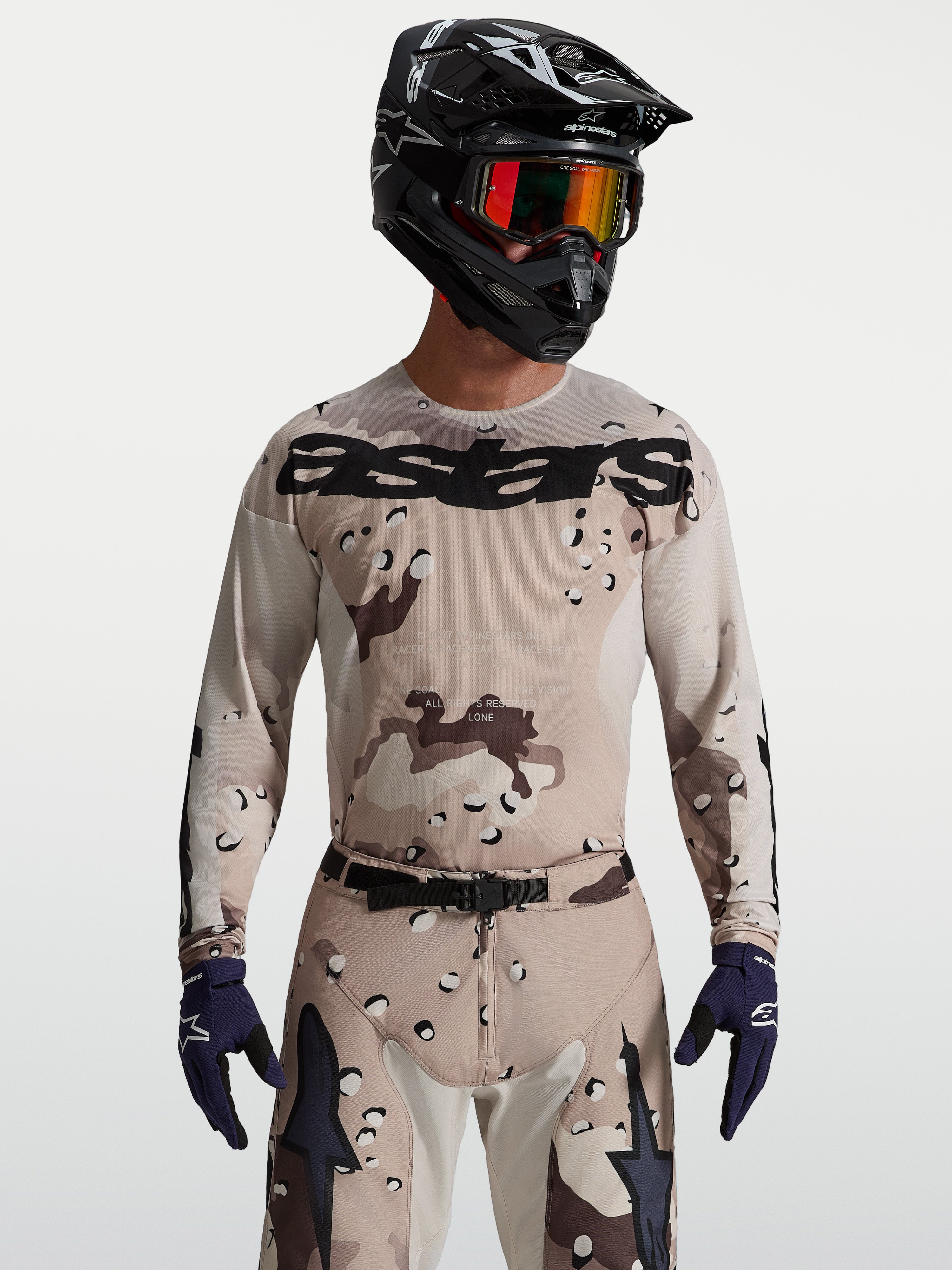 Alpinestars Racer Lone Jersey in Desert Camo and Black, men's motocross gear on model with helmet and goggles.