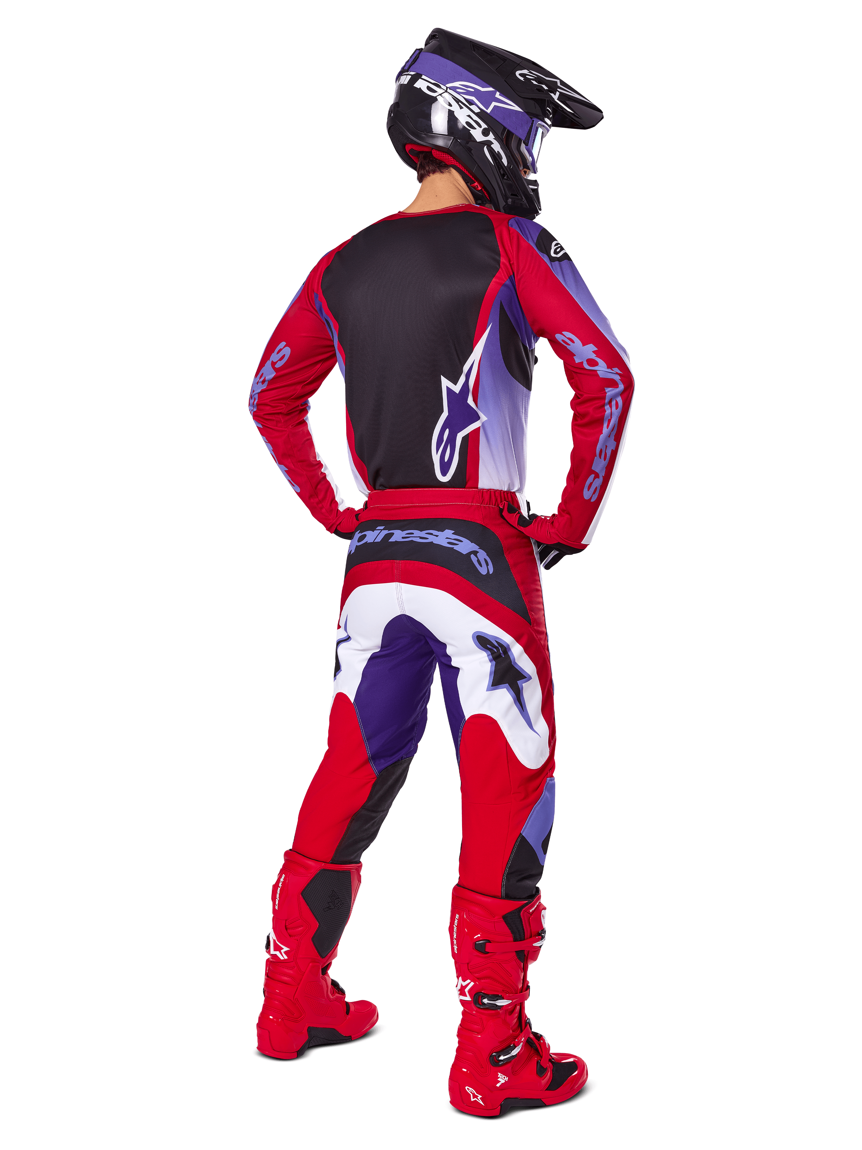 Motocross rider from behind wearing the Alpinestars 2025 Fluid Wurx Gear Set, Purple Bright Red jersey with black back panel, matching motocross pants with white and purple accents, bright red boots, and black helmet, professional off-road racing outfit