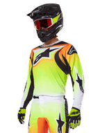 Alpinestars 2025 Fluid Wurx Gear Set, motocross-udstyr, gul og orange gradient jersey med sorte detaljer og store stjernelogoer, matchende motocrossbukser, sort full-face hjelm med røde goggles og gule handsker, koordineret højtydende outfit til off-road kørsel