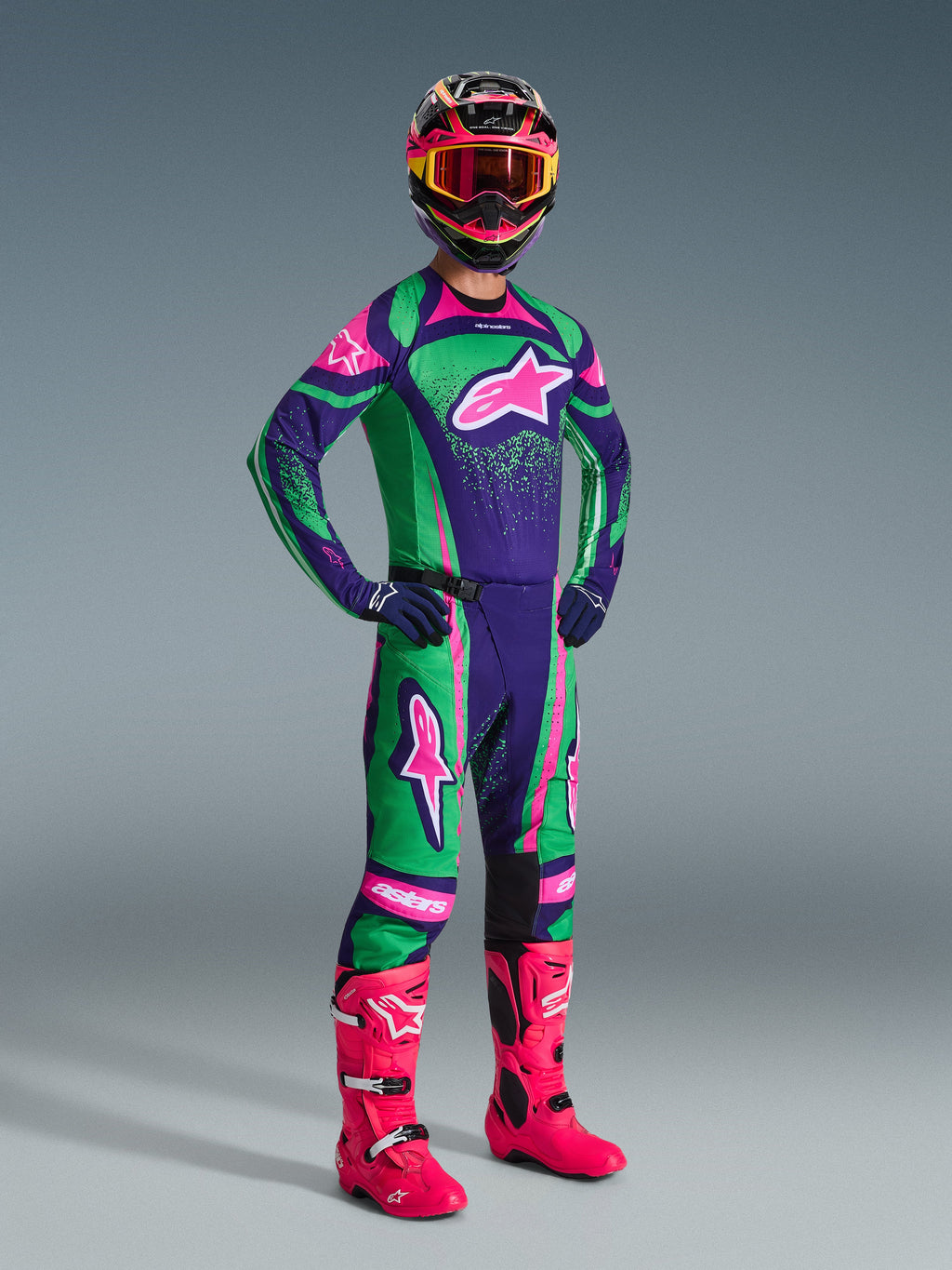 Alpinestars 2026 Techstar Nomur udstyrssæt, motocross-udstyr i mørkelilla, grøn og pink fluo, komplet raceroutfit med matchende trøje og bukser, farverig hjelm med pink crossbriller og klare pink støvler, professionelt off-road racerudstyr