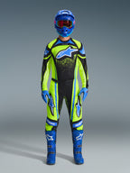 Motocrosskører iført komplet racerudstyr, 2026 Techstar Nomur jersey i gul fluo og mørk navy, matchende motocrossbukser, blå hjelm med rødfarvede goggles, blå handsker og blå støvler, koordineret professionelt outfit til terrænkørsel