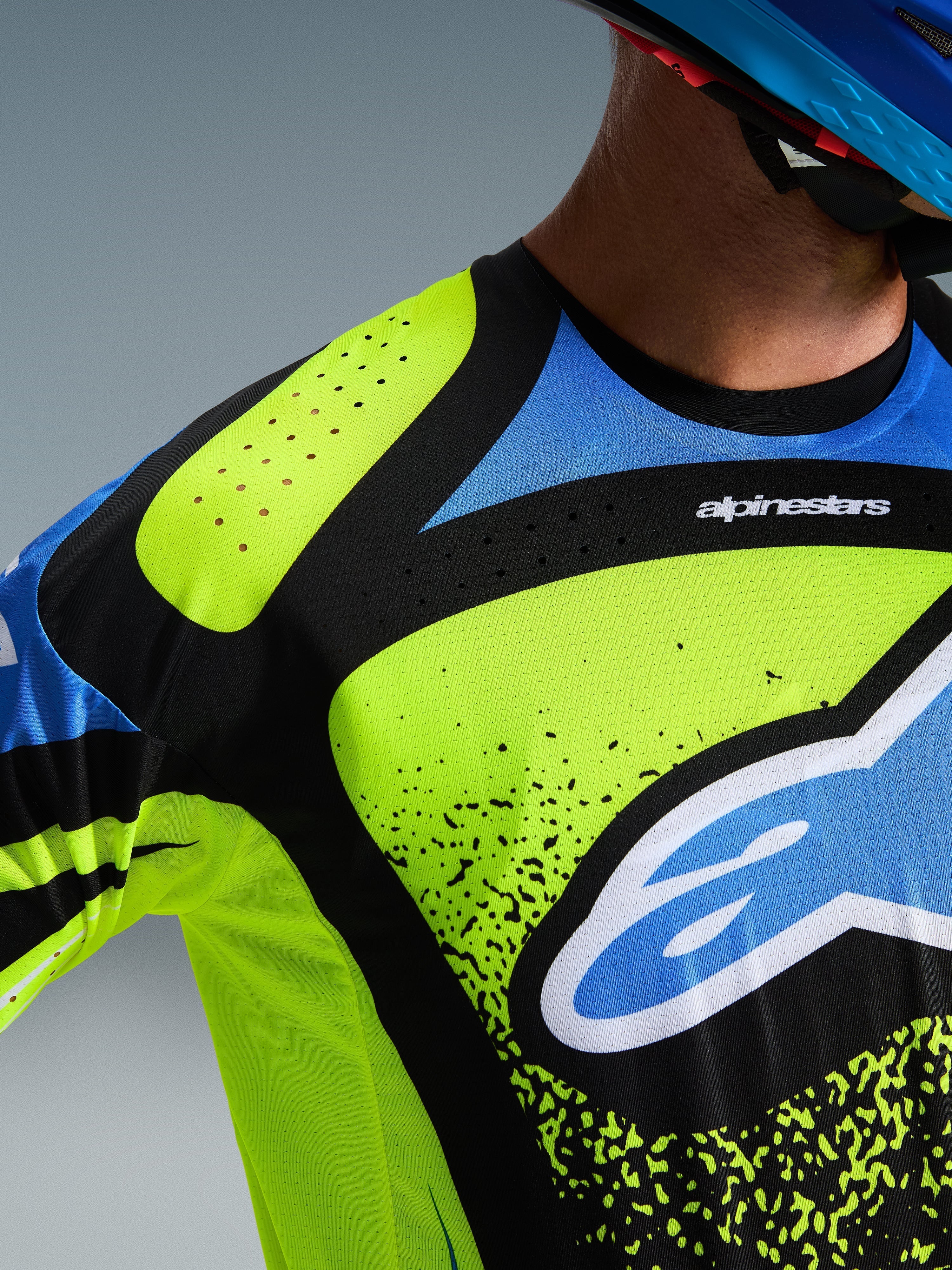 Alpinestars 2026 Techstar Nomur Jersey, motocross-trøje, Yellow Fluo, Dark Navy og UCLA Blue, nærbillede af bryst og skulder, der viser laserskårne perforeringer til ventilation og Alpinestars-logoet, højtydende off-road racingudstyr