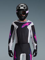 Alpinestars 2026 Fluid Grid trøje, motocross-trøje, sort, lysegrå og lilla, båret af en kører med matchende off-road bukser, sort hjelm og goggles, komplet performance racing-udstyrssæt