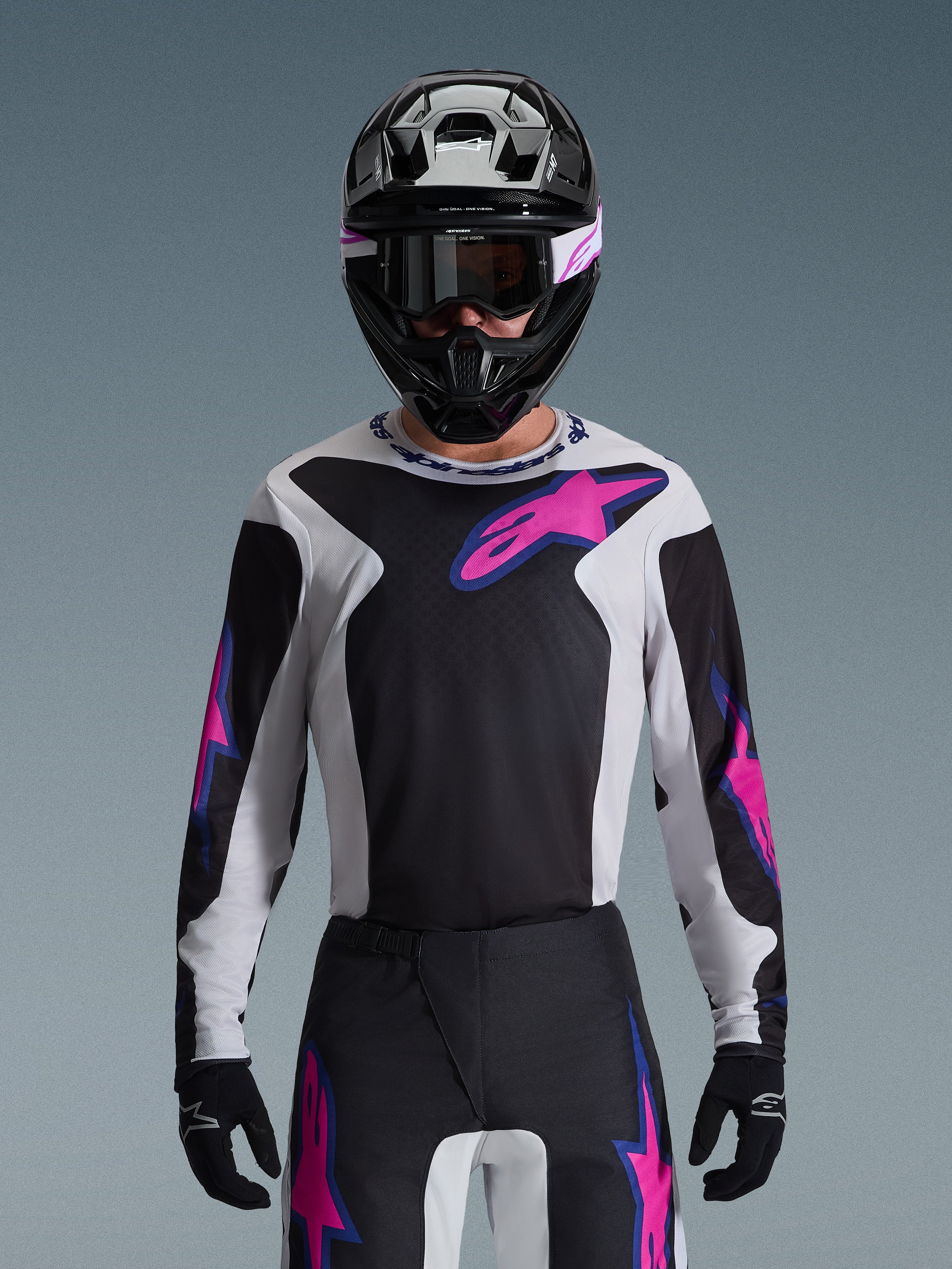 Alpinestars 2026 Fluid Grid trøje, motocross-trøje, sort, lysegrå og lilla, båret af en kører med matchende off-road bukser, sort hjelm og goggles, komplet performance racing-udstyrssæt